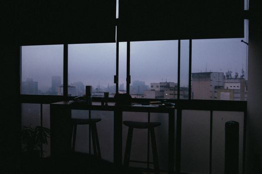 从昏暗的现代办公室内俯瞰城市，天际线灯光朦胧，映照着城市建筑