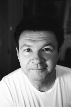 Black and white of sincere middle aged male in casual clothes looking at camera