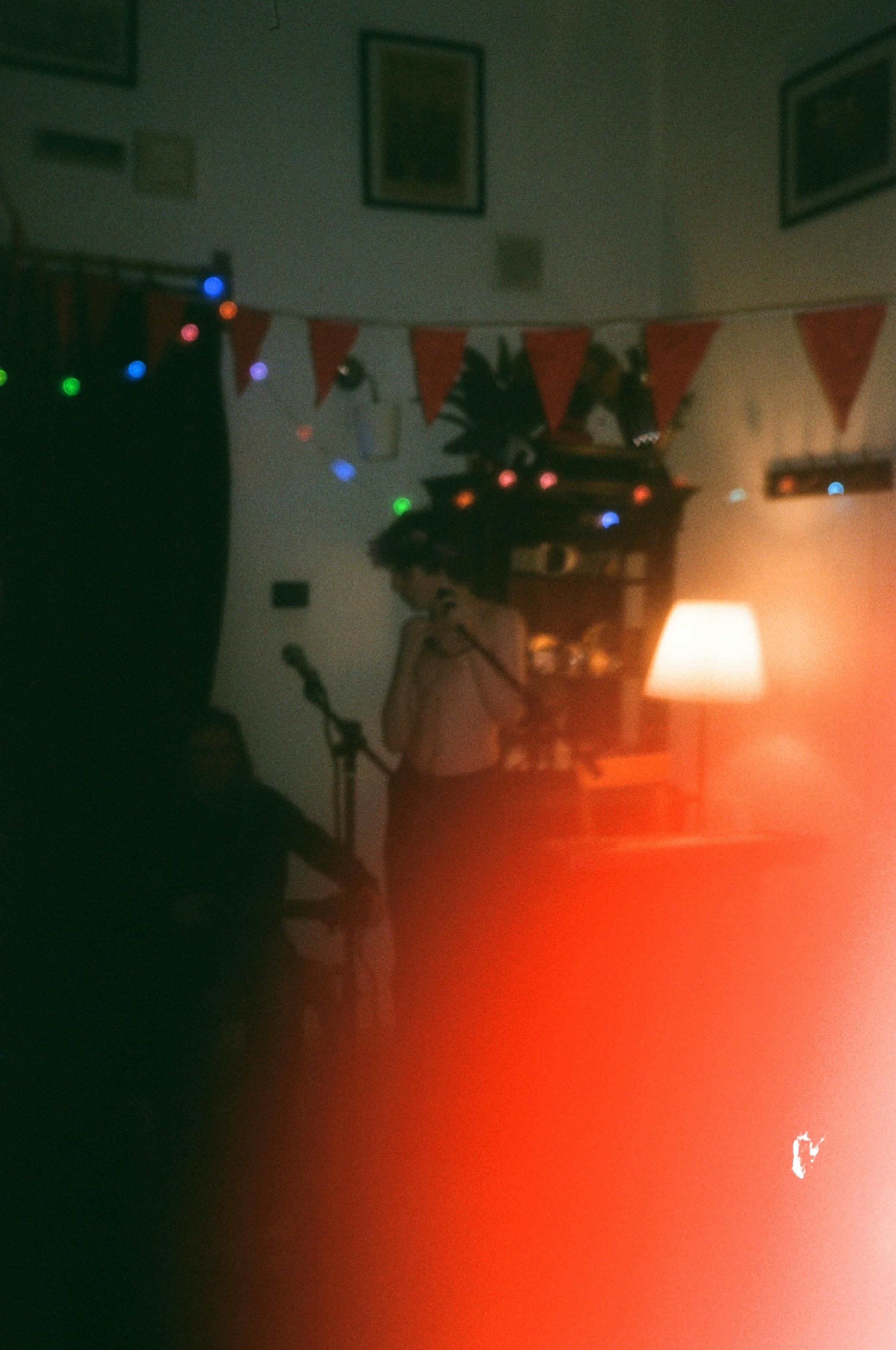 Anonymous male singer with microphone near table with glowing lamp and partner in room with decorative garlands during rehearsal