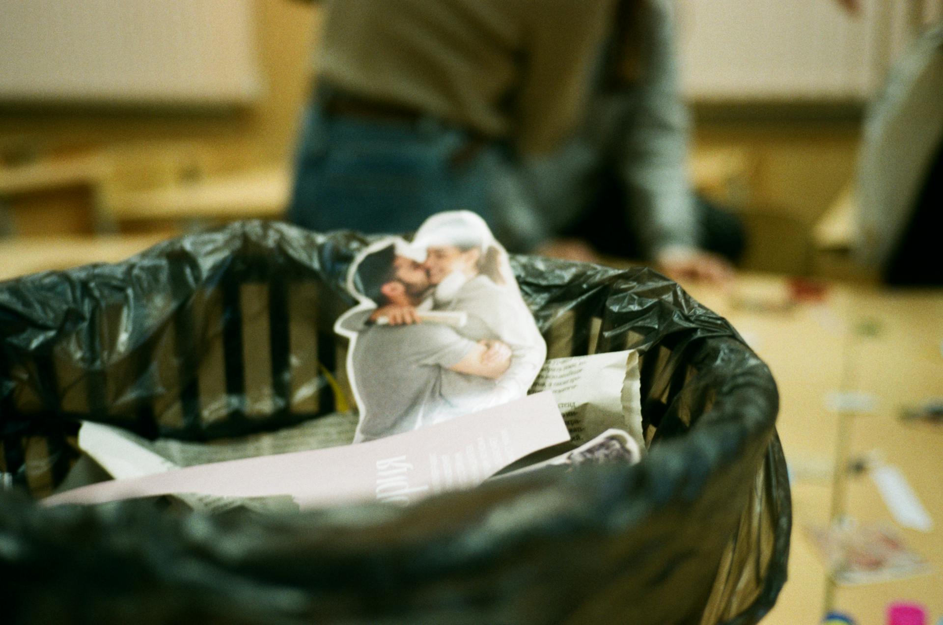 Creative shot of a paper couple in a trash can, symbolizing the end of a relationship.