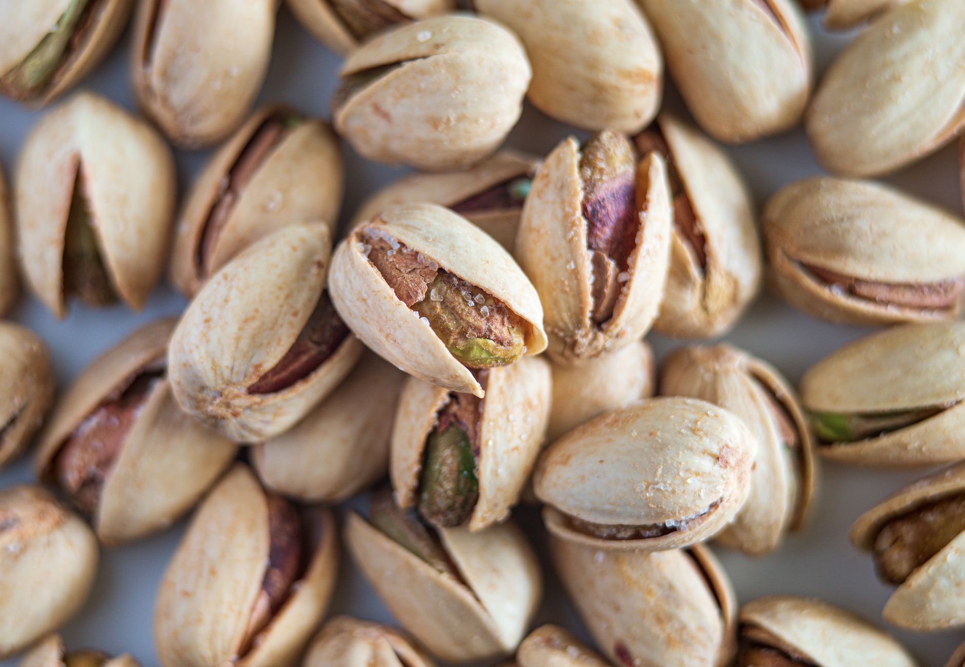 Macro photograph highlighting salted pistachios in their shells, showcasing detail and texture.