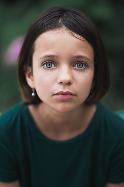Pensive little girl in casual t shirt with short hair looking at camera