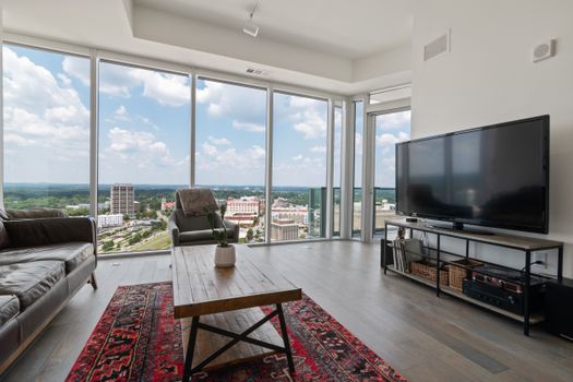 Bright modern living room with large glass windows offering a scenic city view.