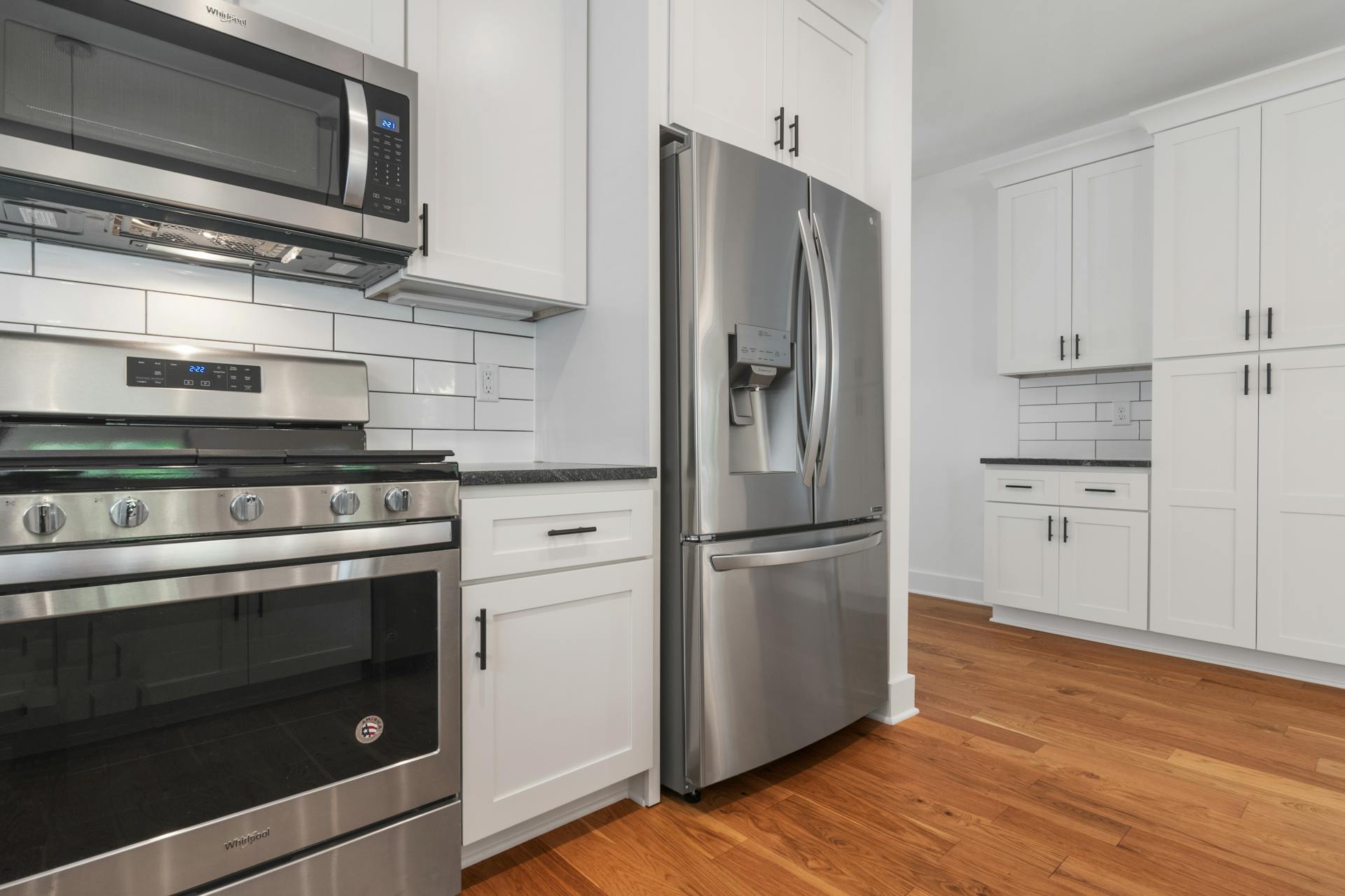 Spacious modern kitchen featuring stainless steel appliances and white cabinetry.