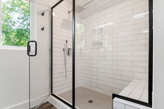 Sleek and modern shower with glass panels and tiled walls in a bright bathroom.