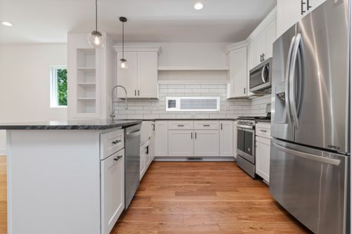 Free Spacious white kitchen featuring modern appliances and wooden flooring for a stylish look. Stock Photo