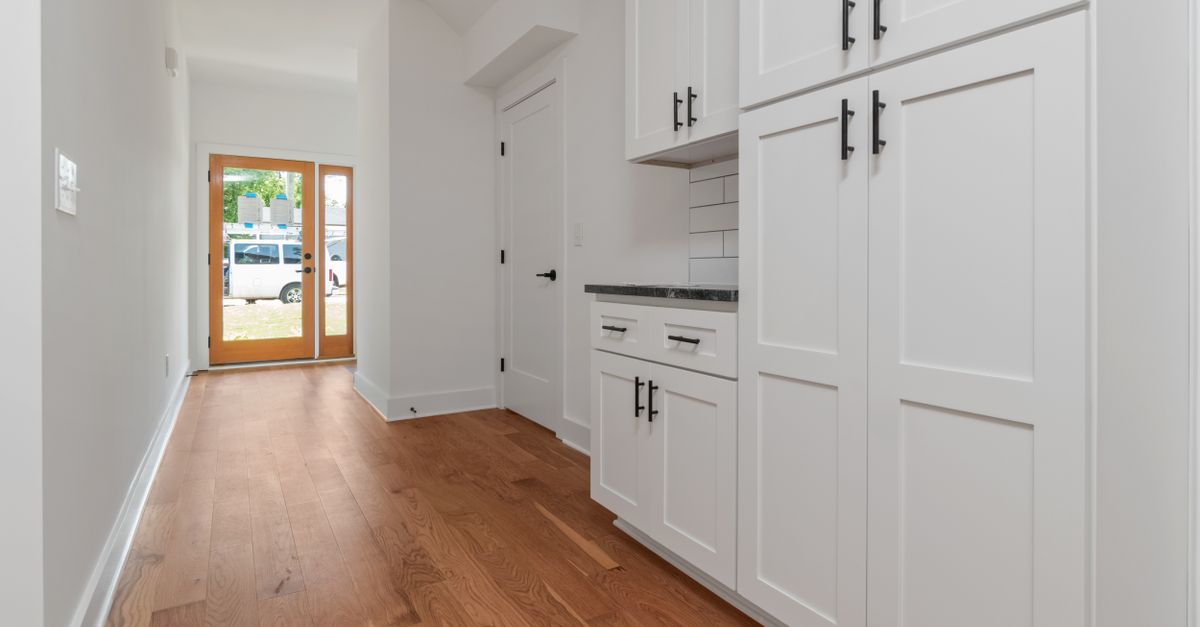 Bright and clean modern kitchen with white cabinets and wooden floors.