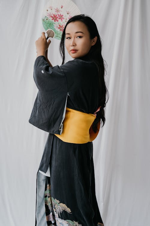 Woman in Black Traditional Clothes Holding a Fan