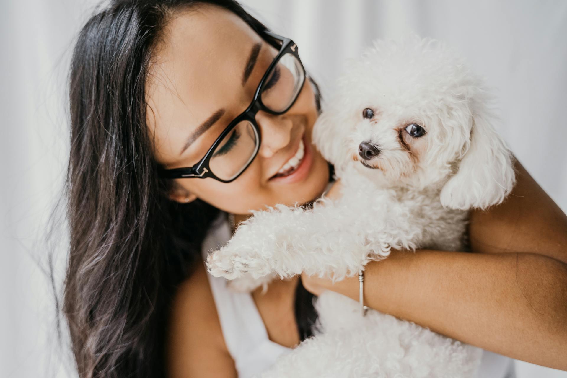 Une femme souriante tenant un caniche