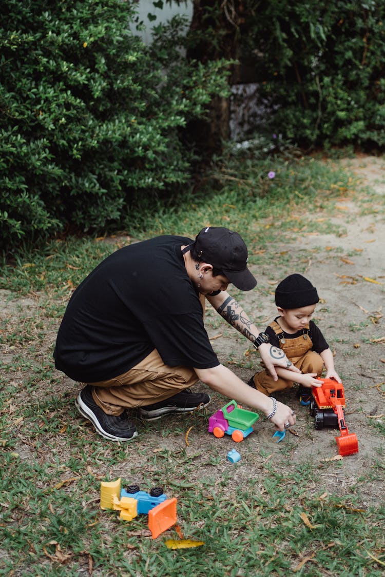 Father And Son Playing With Toy Cars Outside