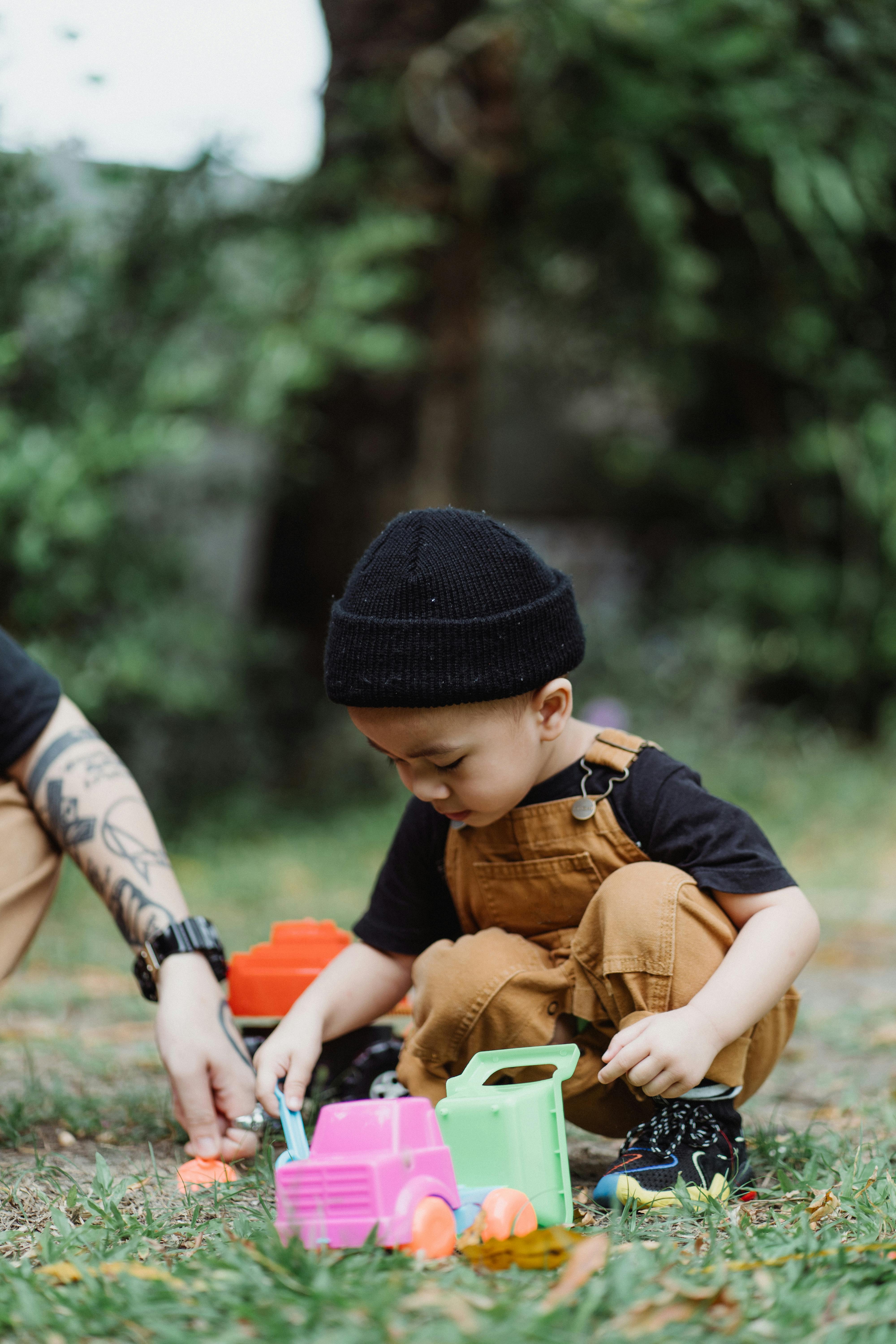 close up of a boy playing with plastic toys on lawn