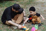 父子俩在户外玩玩具车，亲密相处，享受着随意而快乐的家庭时光