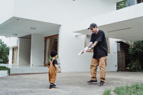 Free A father and son bonding while playing with paper planes outside their modern home. Stock Photo