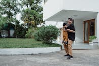 阳光明媚的户外前院，一对快乐的父子正在一起玩耍，画面捕捉到了家庭的团聚