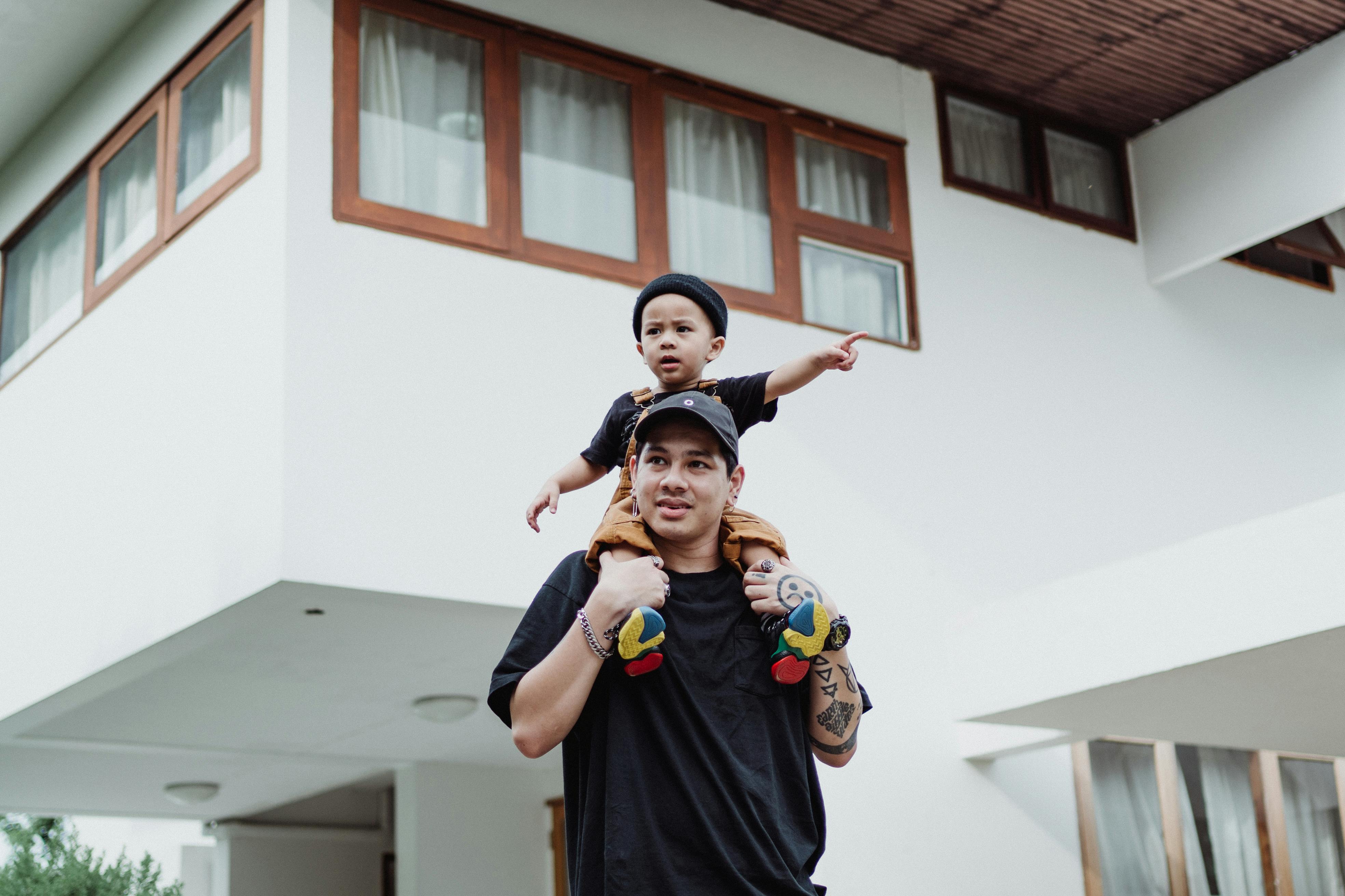 A father carrying his young son on his shoulders, enjoying a playful moment outdoors.
