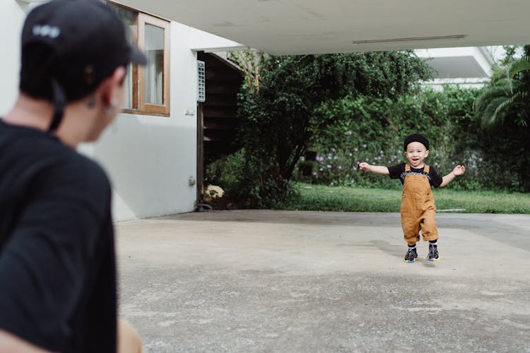 Boy In Dungarees Running To His Father Outside The House