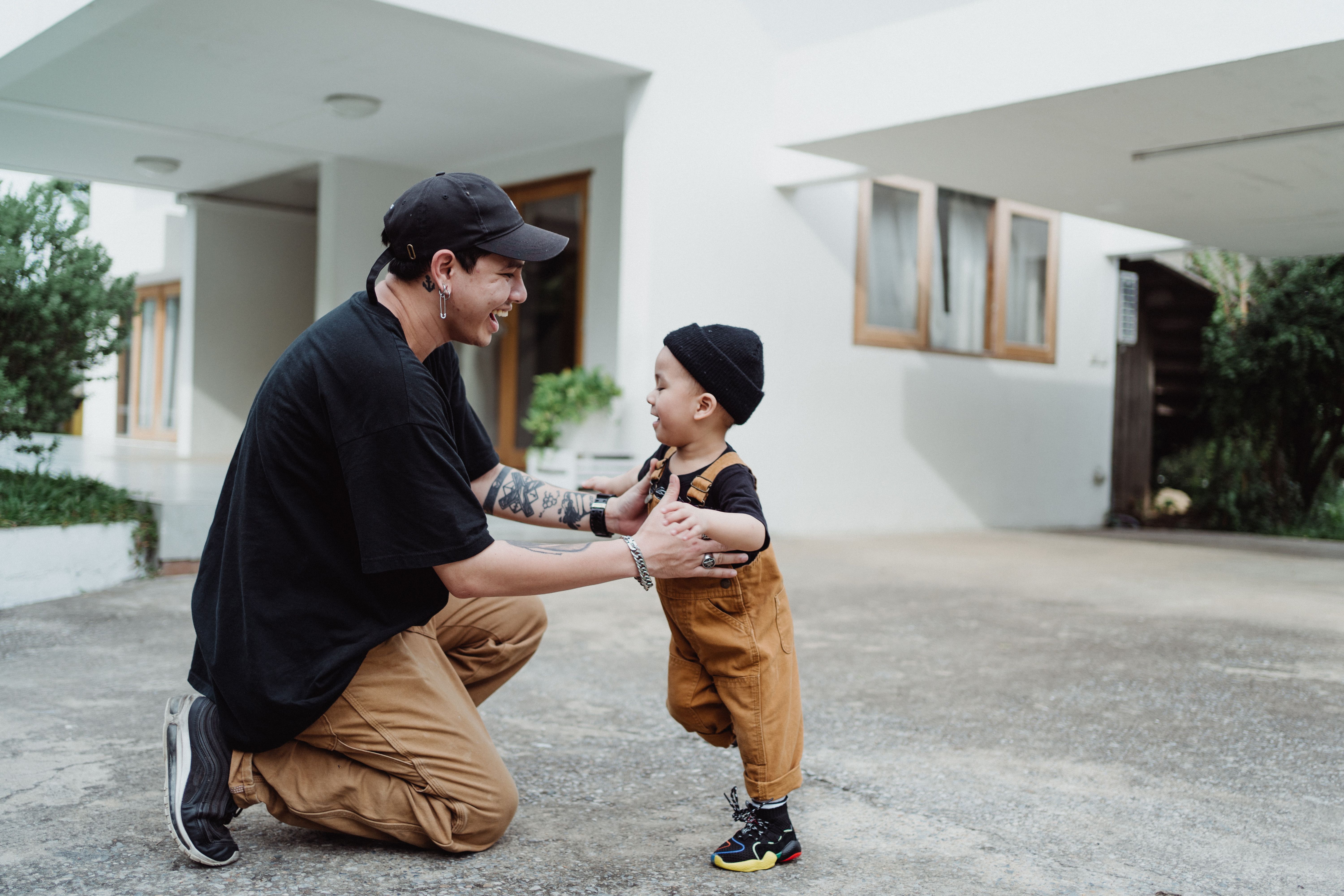 爸爸和年幼的儿子在现代化的房子外玩耍，享受着美好时光