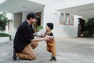 爸爸和年幼的儿子在现代化的房子外玩耍，享受着美好时光