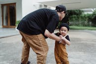 阳光明媚，父子俩在一栋独立屋外欢乐地玩耍