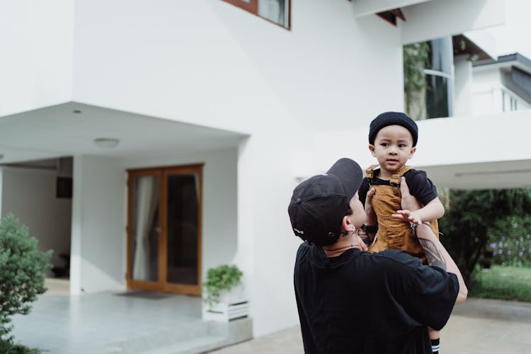 Mother Holding Child Near House