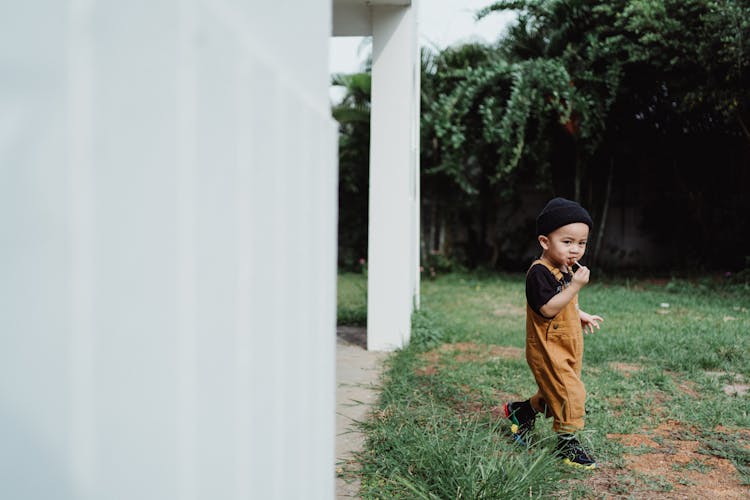 Cute Little Boy Walking On The Backyard And Eating A Lollipop