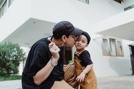 在户外，一位父亲发自内心地深情亲吻了小儿子的脸颊
