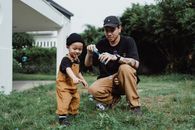Father Blowing Bubbles in Garden with His Son