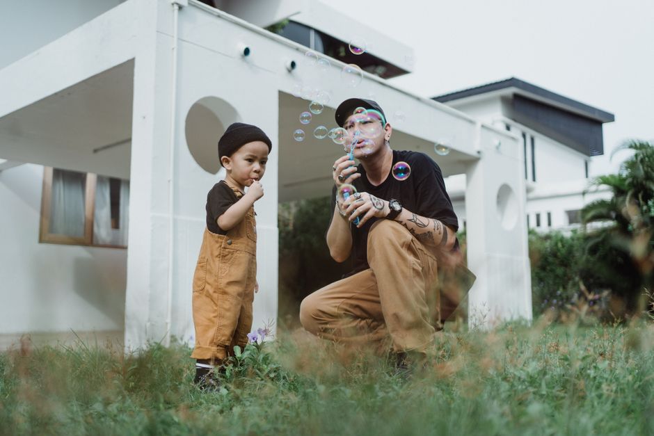 Father and son bond while playing with soap bubbles in the yard. Capturing joyful family moments.