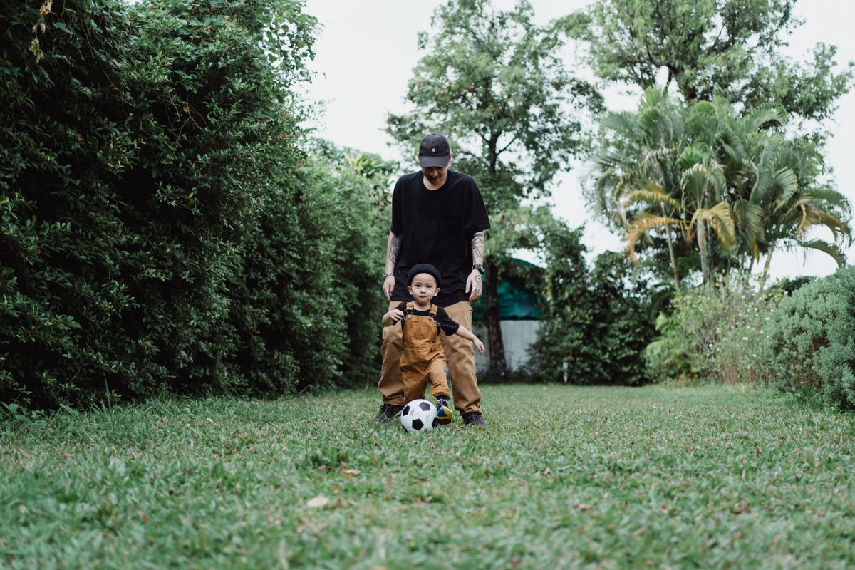 Boy playing soccer with his father in a backyard