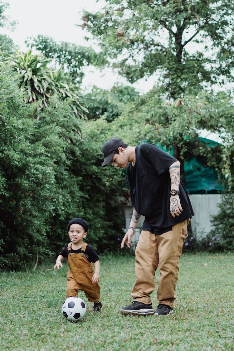 Father And Baby Son Playing Football In The Backyard 
