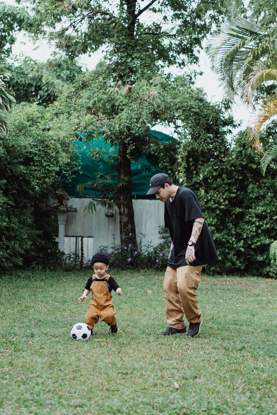 Father and young son playing with a soccer ball in the backyard