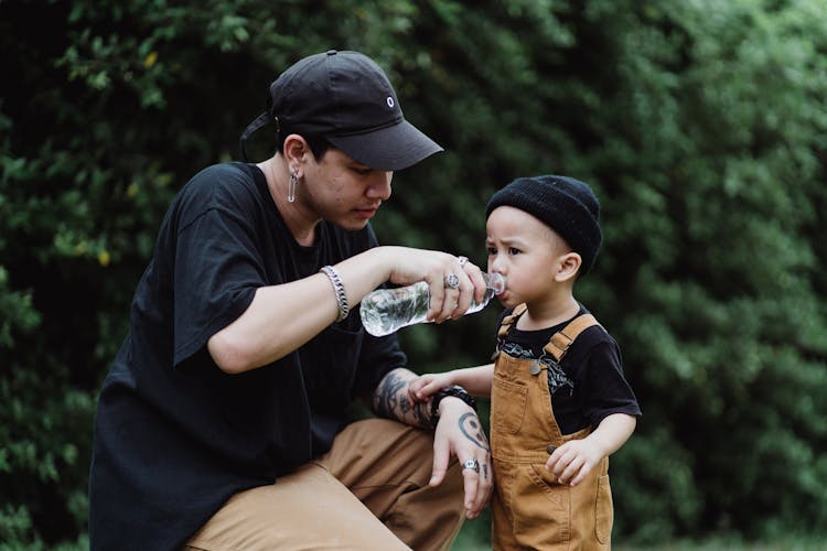 A Boy Drinking Water From A Bottle