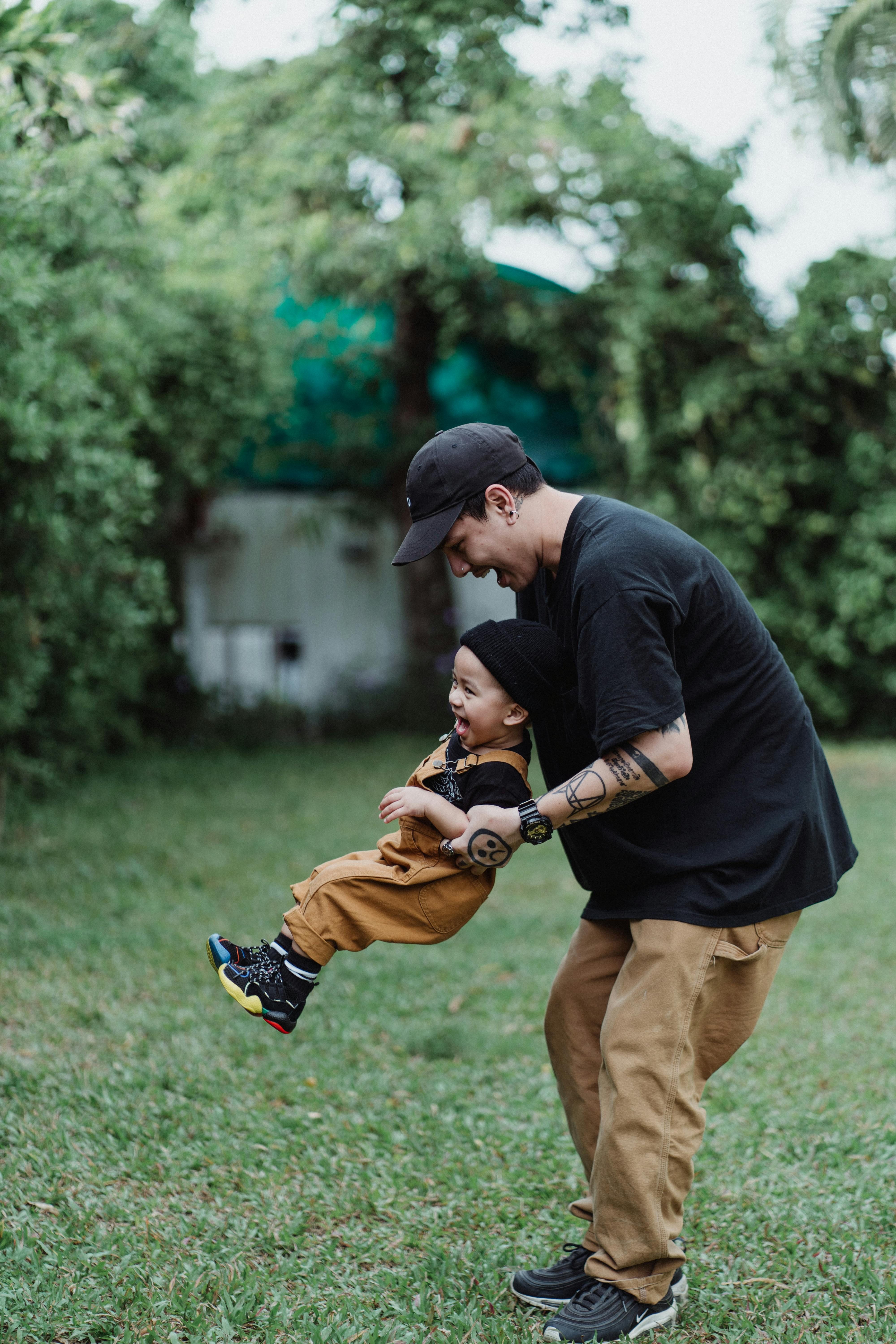 Man in Black TShirt and Brown Pants Circling Boy in Brown Overall  Free  Stock Photo