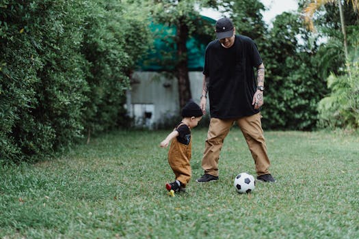 A father and son enjoy a game of soccer on a grassy field, showcasing bonding and fun.