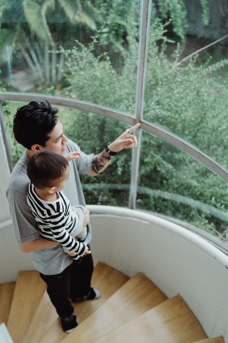 Father And Son Walking Up Stairs Looking At Forest Outside