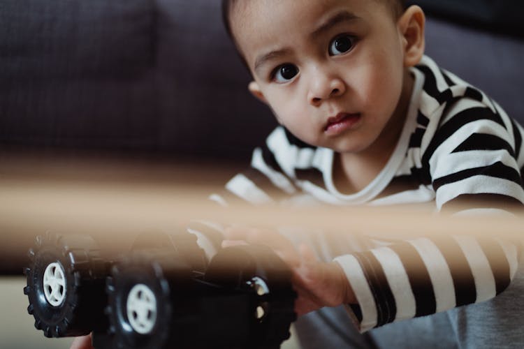 Little Boy Playing With A Toy Car 