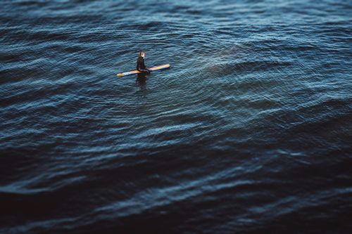 Free A lone surfer in a wetsuit paddling on tranquil ocean waves off Santa Barbara. Stock Photo