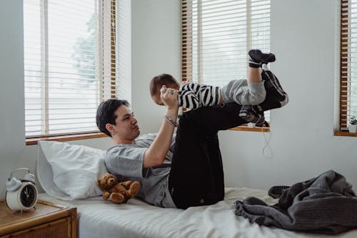 Father Playing with his Little Son in Bed 