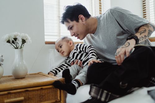 Free A father and son bonding indoors, showcasing a modern and loving family moment. Stock Photo