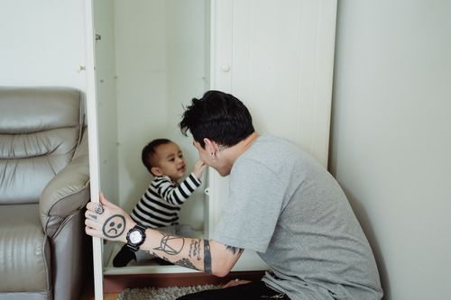 Free A father and son enjoy a playful moment in a wardrobe, showcasing family bonding. Stock Photo