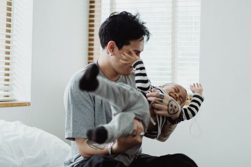 Free A father playfully holding his son indoors, showcasing family bonding and joy. Stock Photo