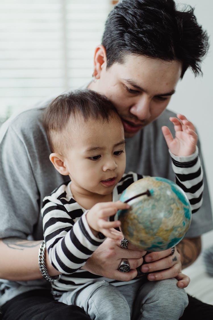 Father Teaching Geography To His Son With Use Of Globe