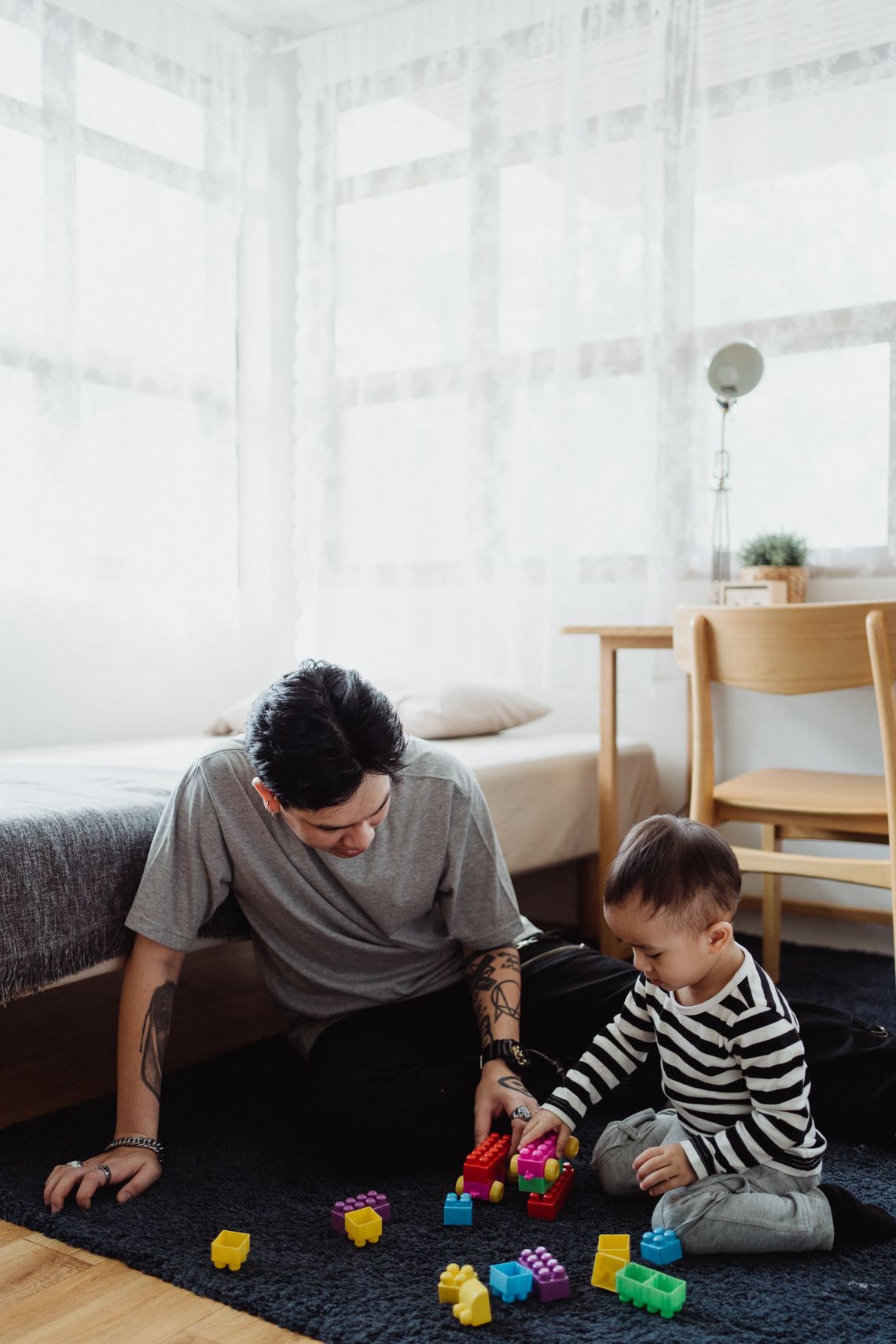 Father and young son enjoying creative building play with colorful blocks