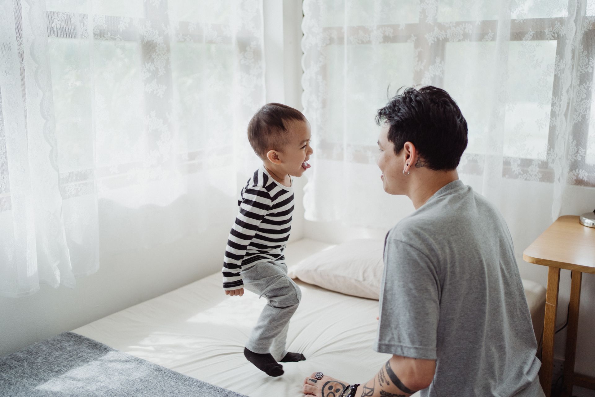 A father and son enjoying quality bonding time at home on the bed in a bright room.