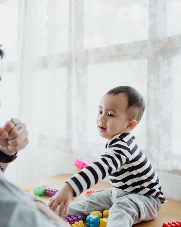 A toddler in a striped top playing with colourful building blocks