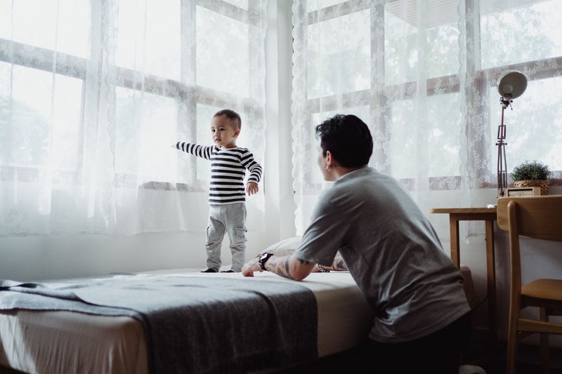 A father engages with his son in a bright and cozy bedroom setting, emphasizing family time.