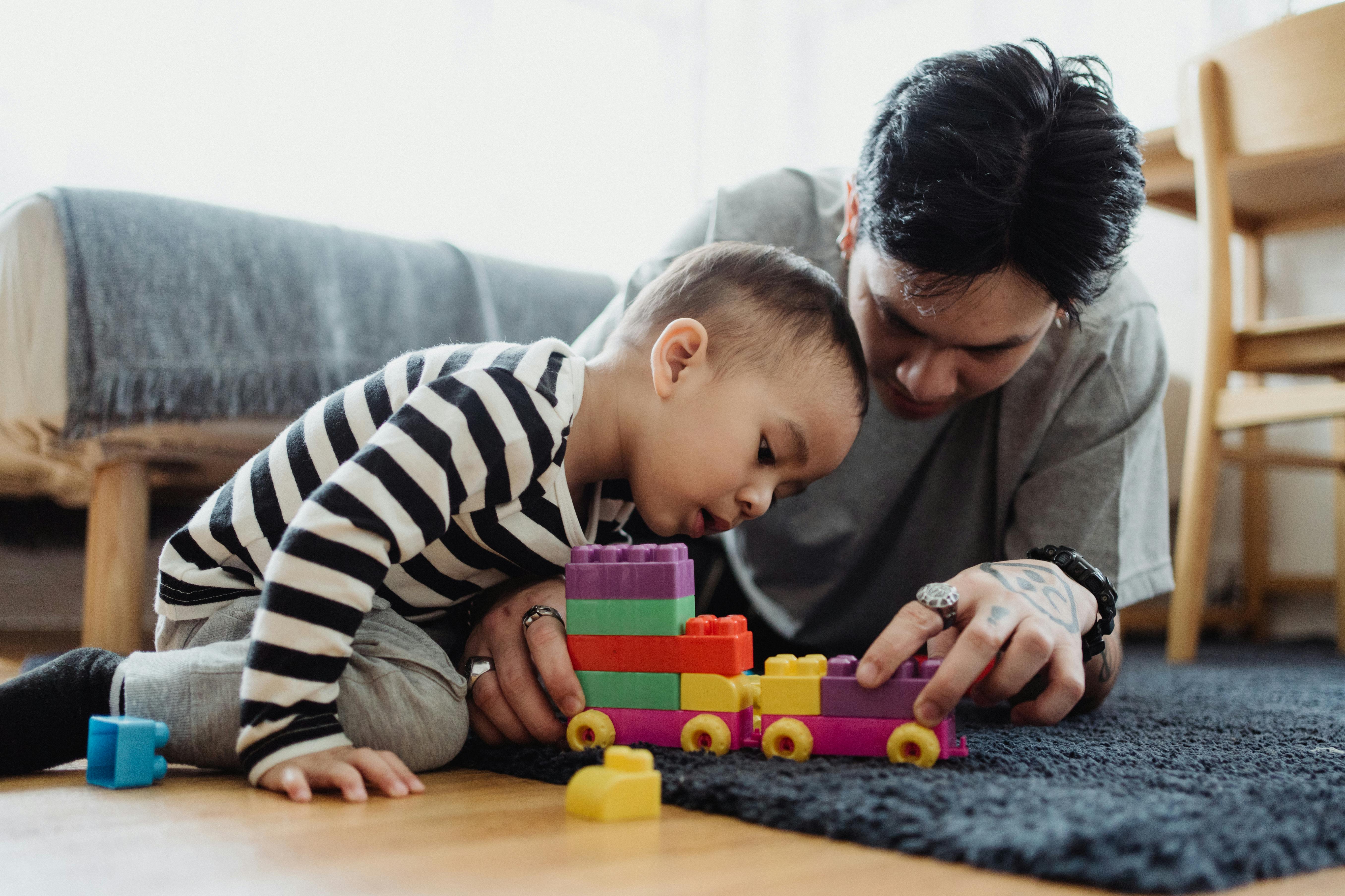 adult respite care - A father and son bonding while playing with colorful blocks indoors.