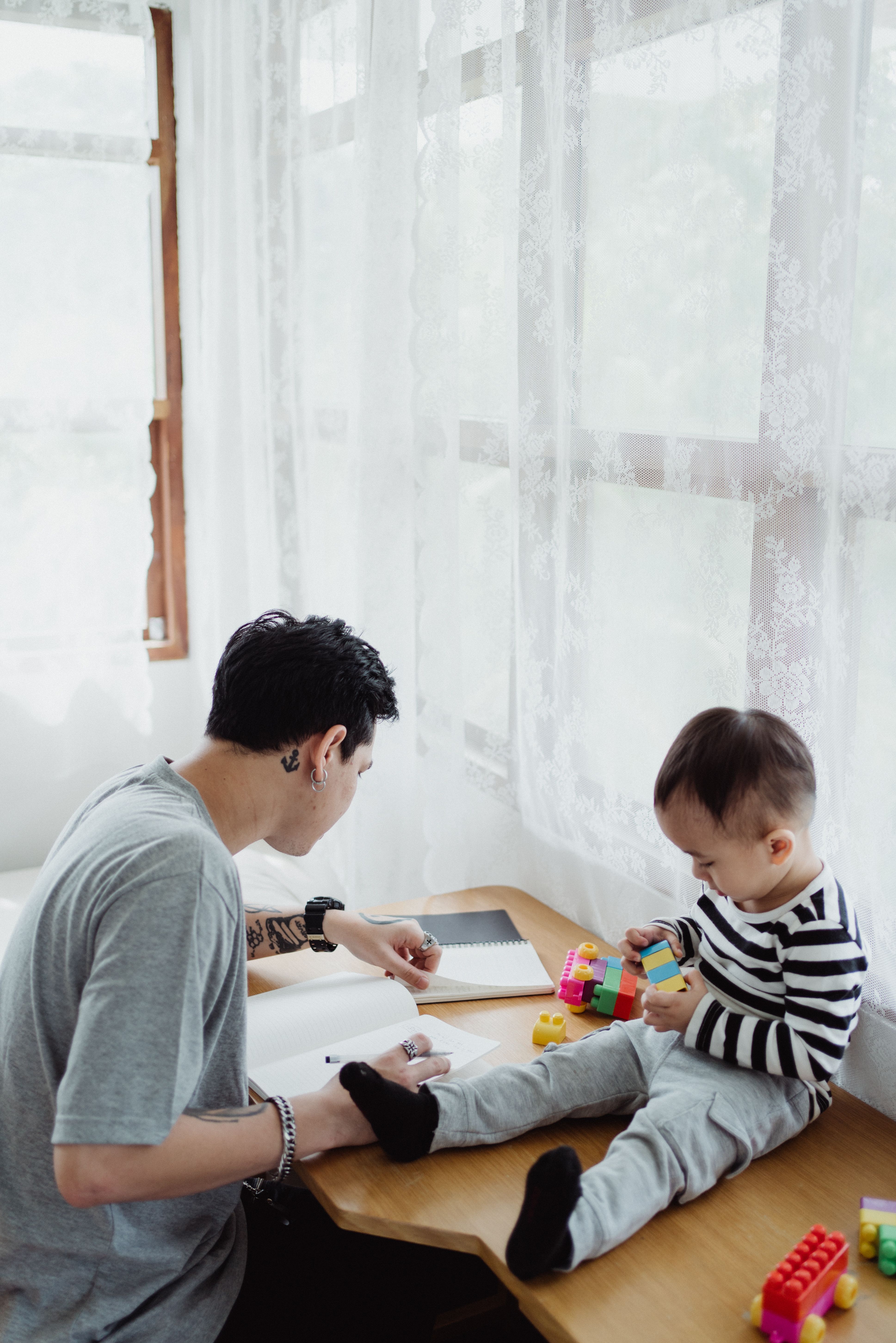一位父亲一边在家处理多项任务，一边与顽皮的幼儿互动
