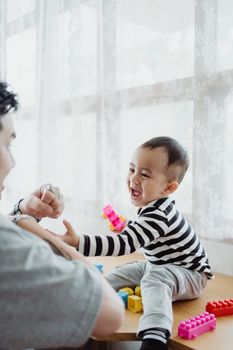 父亲和孩子在窗前玩积木，这是他们建立联系的快乐时刻