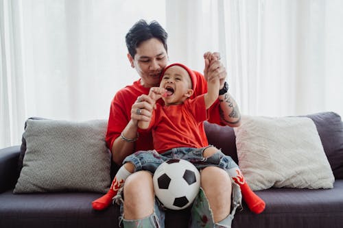 Father and Son Dressed in Red Playing on Sofa